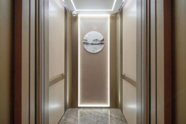Un couloir étroit et bien éclairé, doté d’un sol en marbre et orné d’une œuvre d’art circulaire au mur.