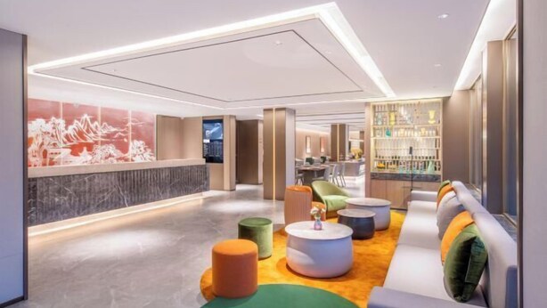 A modern lobby with a reception desk, seating area, and a bar. - Orange Hotel (Beijing West Railway Station) (Beijing)