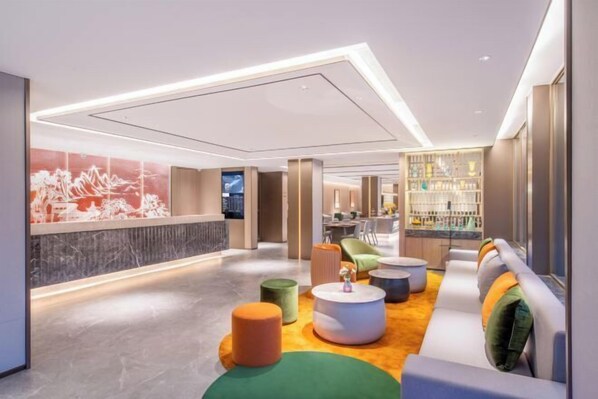 Un lobby moderno con una recepción, zona de estar y un bar.