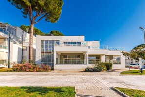 Un edificio moderno con techo plano, ventanas grandes y un balcón con barandas azules.