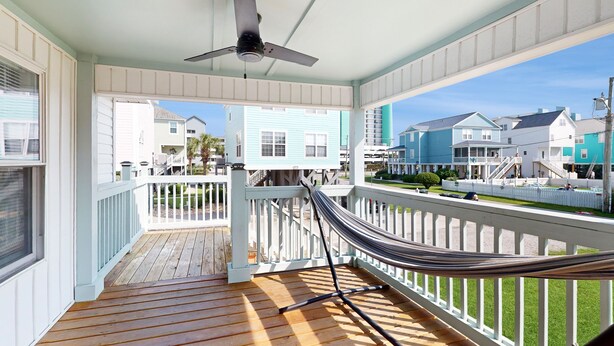 A covered porch with a hammock, wooden deck, and a view of neighboring houses. - Charming duplex with balcony,  W/D, central AC & steps to beach (Murrells Inlet)