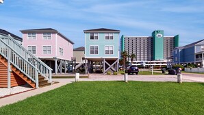 A beachfront hotel with colorful buildings, a covered walkway, and a parking area. - Charming duplex with balcony,  W/D, central AC & steps to beach (Murrells Inlet)