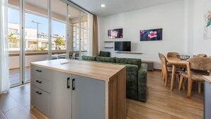 Um apartamento moderno com cozinha, sala de jantar e sala de estar com sofá e TV.