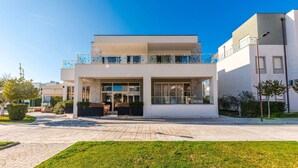 Un bâtiment moderne à deux étages, doté d’un toit plat, de grandes fenêtres et d’un balcon agrémenté de touches de bleu.