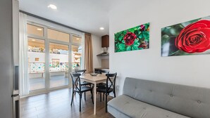 Una sala de estar moderna con un sofá gris, una mesa de comedor con sillas y dos grandes cuadros florales en la pared.