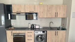 A modern kitchen with wooden cabinets, a Bosch dishwasher, a Bosch washing machine, a microwave, and a sink. - Modern, safe and very clean self catering apartment . (Gaborone)