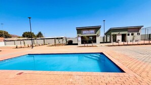 A swimming pool area with a Lifestyle Centre building in the background. - Modern, safe and very clean self catering apartment . (Gaborone)