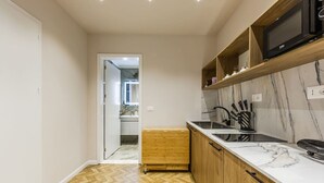 A modern kitchen with wooden cabinets, a marble countertop, and a built-in microwave. - 1 Bedroom Loft - Serenitas 1 by PikHost (Tiranë)