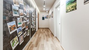 A hallway with a wooden floor, white walls, and various photographs displayed on the walls. - 1 Bedroom Loft - Serenitas 1 by PikHost (Tiranë)
