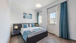 A modern bedroom with a large bed, bedside tables with lamps, a window with curtains, and a ceiling light. - Spacious 1BR Apartment with Resort Access by PikHost (Gjiri i Lalzit)