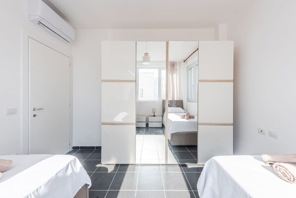 A hotel room with a bed, a nightstand, a mirror, and a wardrobe.