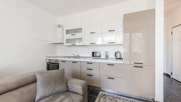 A modern kitchen with white cabinets, a microwave, and a kettle on the counter.