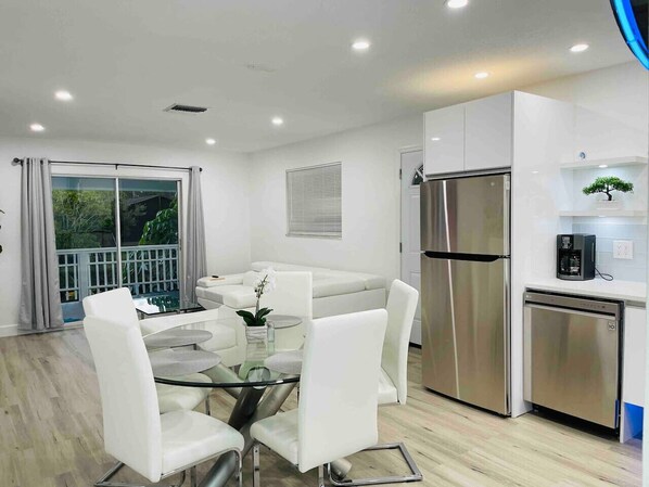 A modern kitchen with a stainless steel refrigerator, a dishwasher, and a coffee machine.
