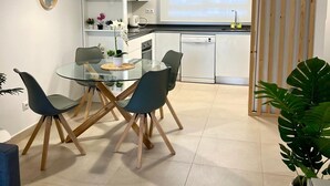 A modern kitchen with white cabinets, a glass dining table, and a view of the city through a large window. - Marina Real in Denia (Denia)