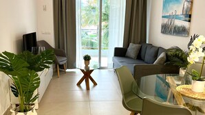 A modern living room with a sofa, dining table, chairs, and a large window with curtains. - Marina Real in Denia (Denia)