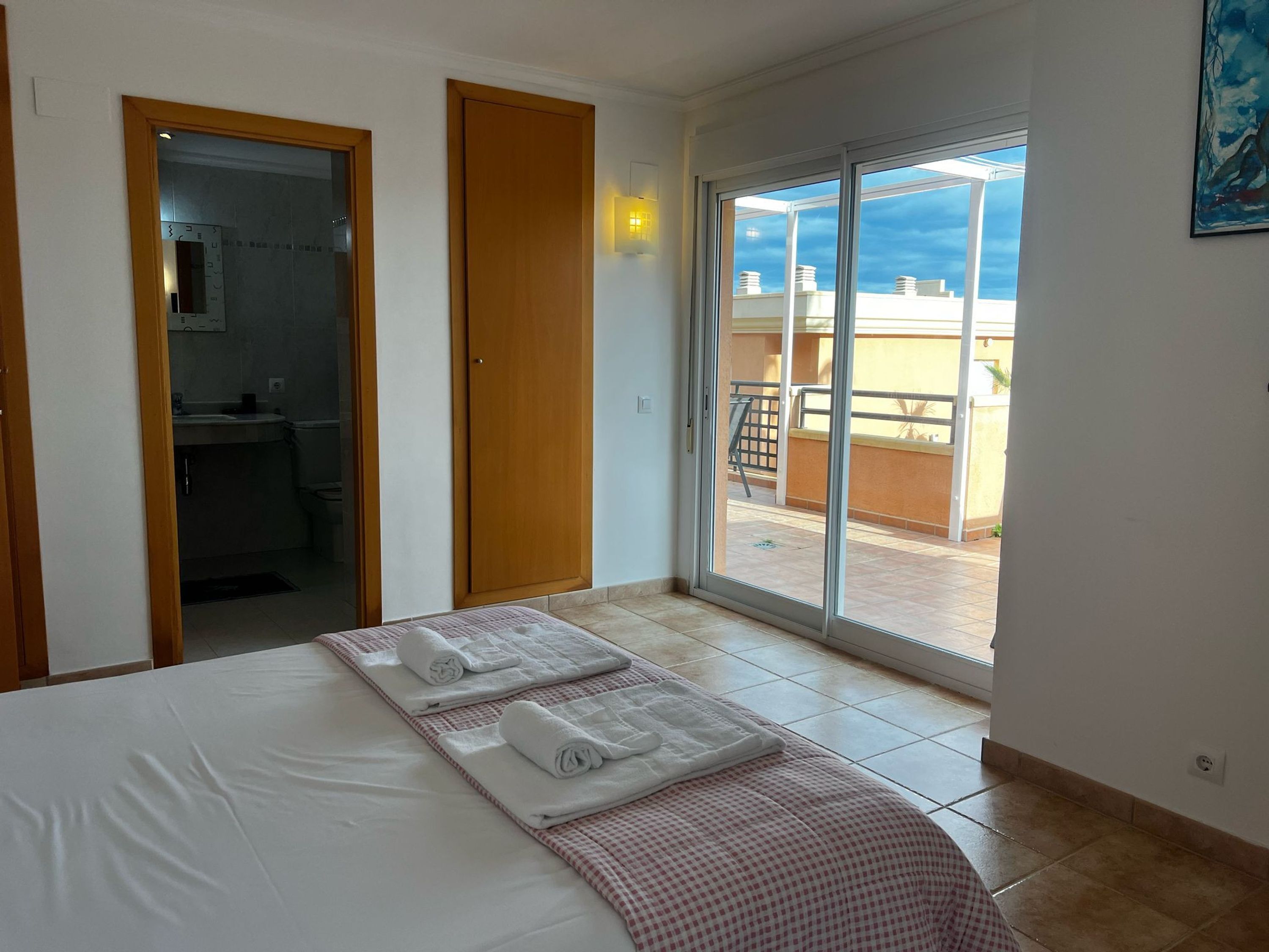 A hotel room with a bed, a bathroom, and a balcony with a view.