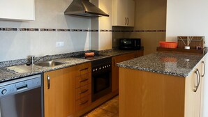 A compact kitchen with a dishwasher, oven, microwave, and a stainless steel range hood. - Jacaranda in Pedreguer (Pedreguer)