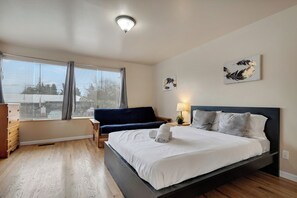 A modern bedroom with a large bed, a sofa, and a desk.