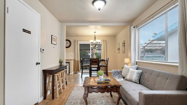 A living room with a sofa, coffee table, and a dining area with chairs and a table. - Brighton House - Walk to Metro (Seattle)
