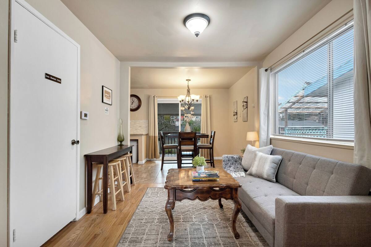 A living room with a sofa, coffee table, and a dining area with chairs and a table.