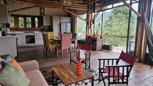 A spacious living area with a wooden floor, a sofa with colorful cushions, a coffee table, and a dining area with chairs and a table. - Casa Tien (Salento)