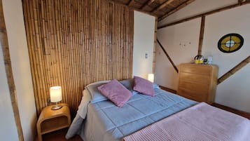 Une chambre à coucher comprenant un lit, deux lampes de chevet, une table de chevet en bois, une commode en bois et un panneau mural en bambou.