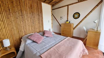 A room with a bed, a wooden dresser, a nightstand, and a wall with a circular decorative item.