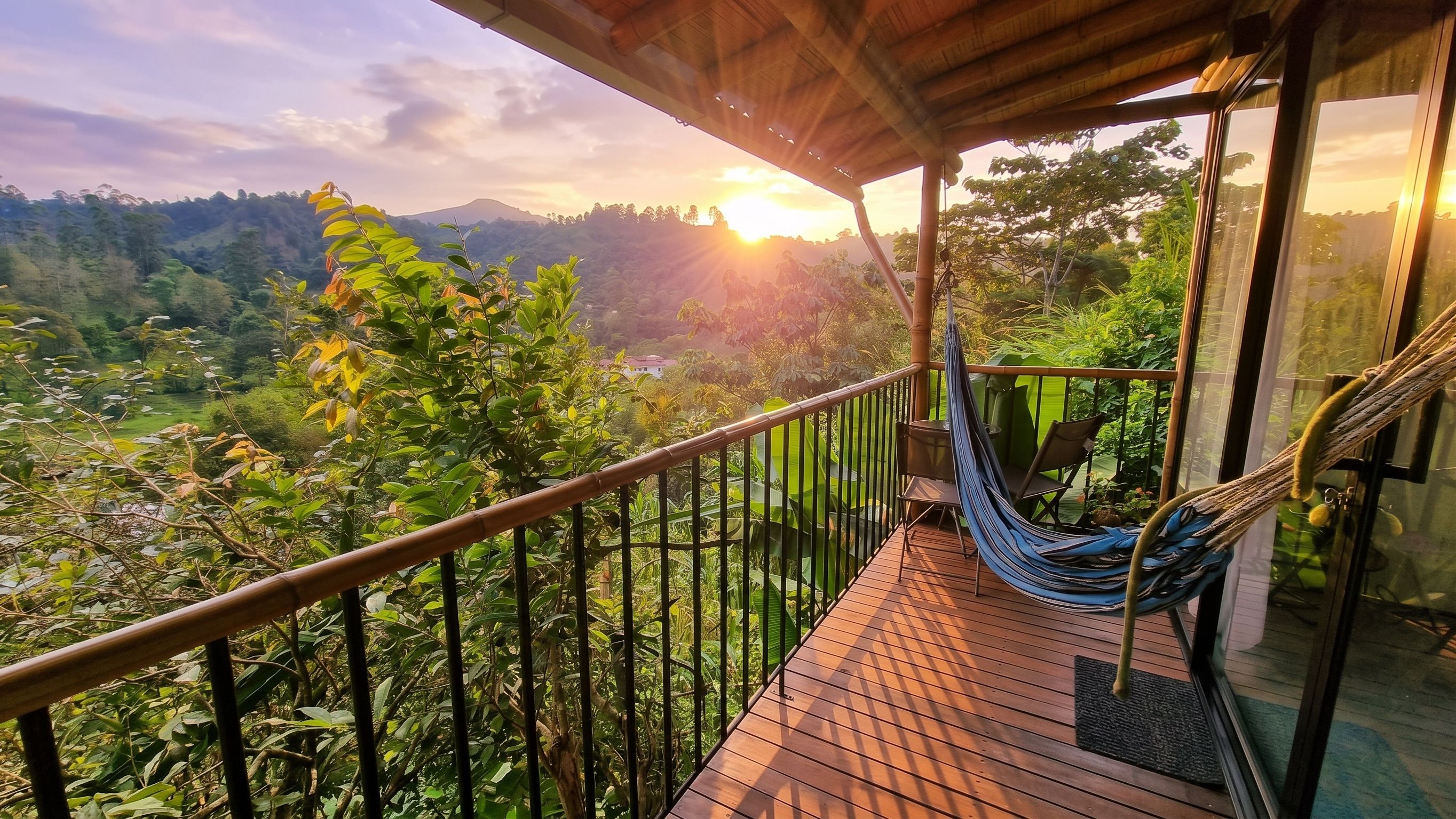 Una terraza de madera con una hamaca, con vista a un exuberante valle y montañas.