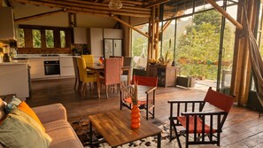 Un interior moderno con comedor, cocina y ventanas amplias que dan a zonas verdes.