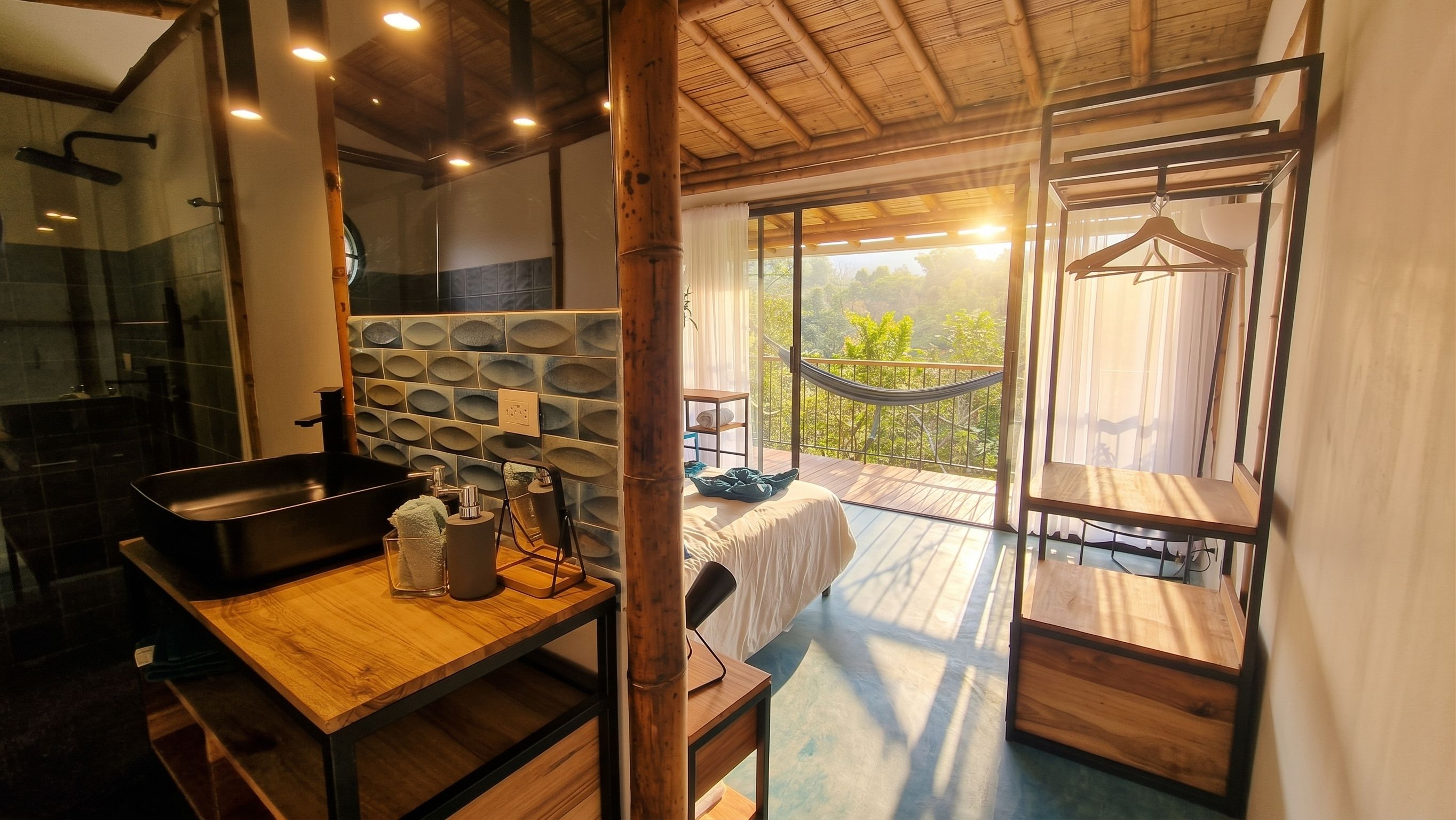 Ein modernes Badezimmer mit Dusche, Waschbecken und Spiegel. Ein Balkon mit Hängematte und Tisch ist ebenfalls vorhanden.