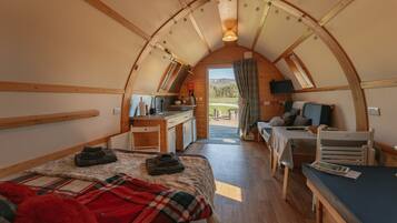 A cozy, semi-open arched room with a bed, a desk, and a table.