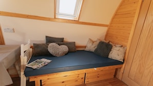 A cozy room with a built-in bed, wooden flooring, and a skylight.