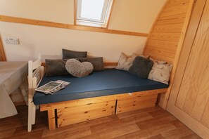 Una habitación acogedora con una cama empotrada, suelo de madera y un tragaluz.