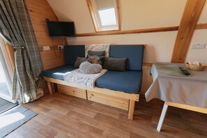 Una habitación acogedora con una cama de madera, una mesita pequeña, un televisor montado en la pared y una ventana con vistas.