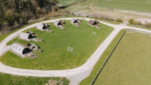 An aerial view of a rural property with multiple farmhouses, a central grassy area, and a surrounding road.
