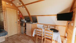 Une pièce compacte comprenant un coin cuisine, un espace repas et un téléviseur fixé au mur.