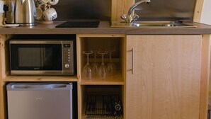 A compact kitchen with a microwave, kettle, and sink. - Cosy Rural Cabin with Private Hot Tub (Thirsk)