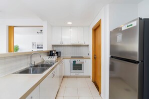 A modern kitchen with white cabinets, stainless steel appliances, and a tiled backsplash.