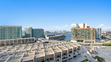 A modern hotel with multiple floors, a marina in the background, and a clear sky.