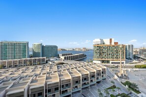 A modern hotel with multiple floors, a marina in the background, and a clear sky. - Bloomfields Stylish 1BR in Al Raha Beach (Abu Dhabi)