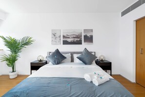 A modern bedroom with a bed, two nightstands, a potted plant, and artwork on the wall. - Bloomfields Stylish 1BR in Al Raha Beach (Abu Dhabi)