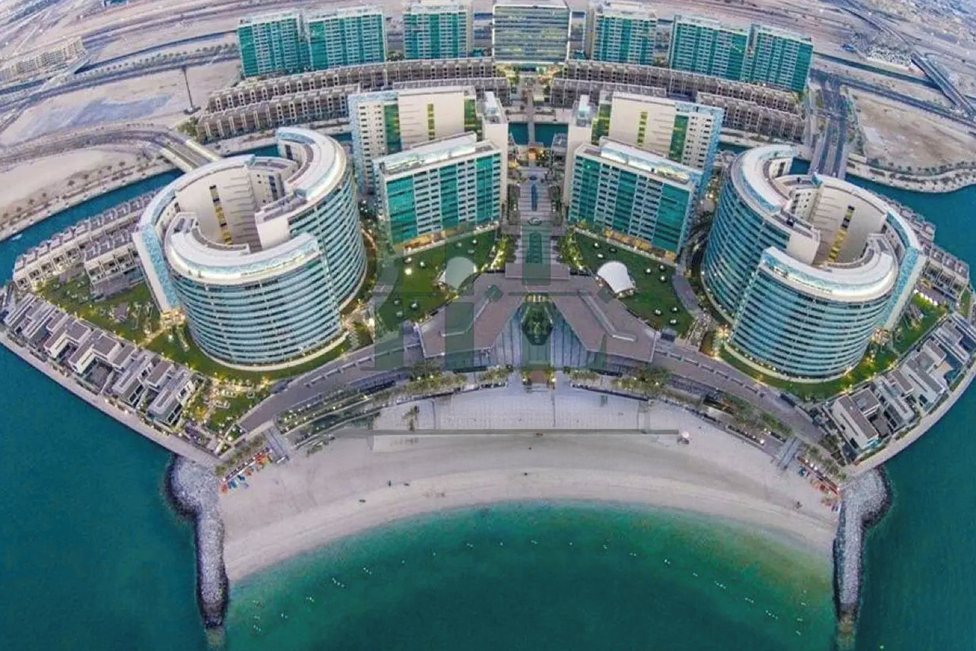 A waterfront hotel complex with multiple high-rise buildings, a central courtyard, and a beach area.