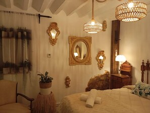 Ein Schlafzimmer mit einem großen Bett, zwei Wandleuchten, einem Spiegel und einem Nachttisch mit Lampe.