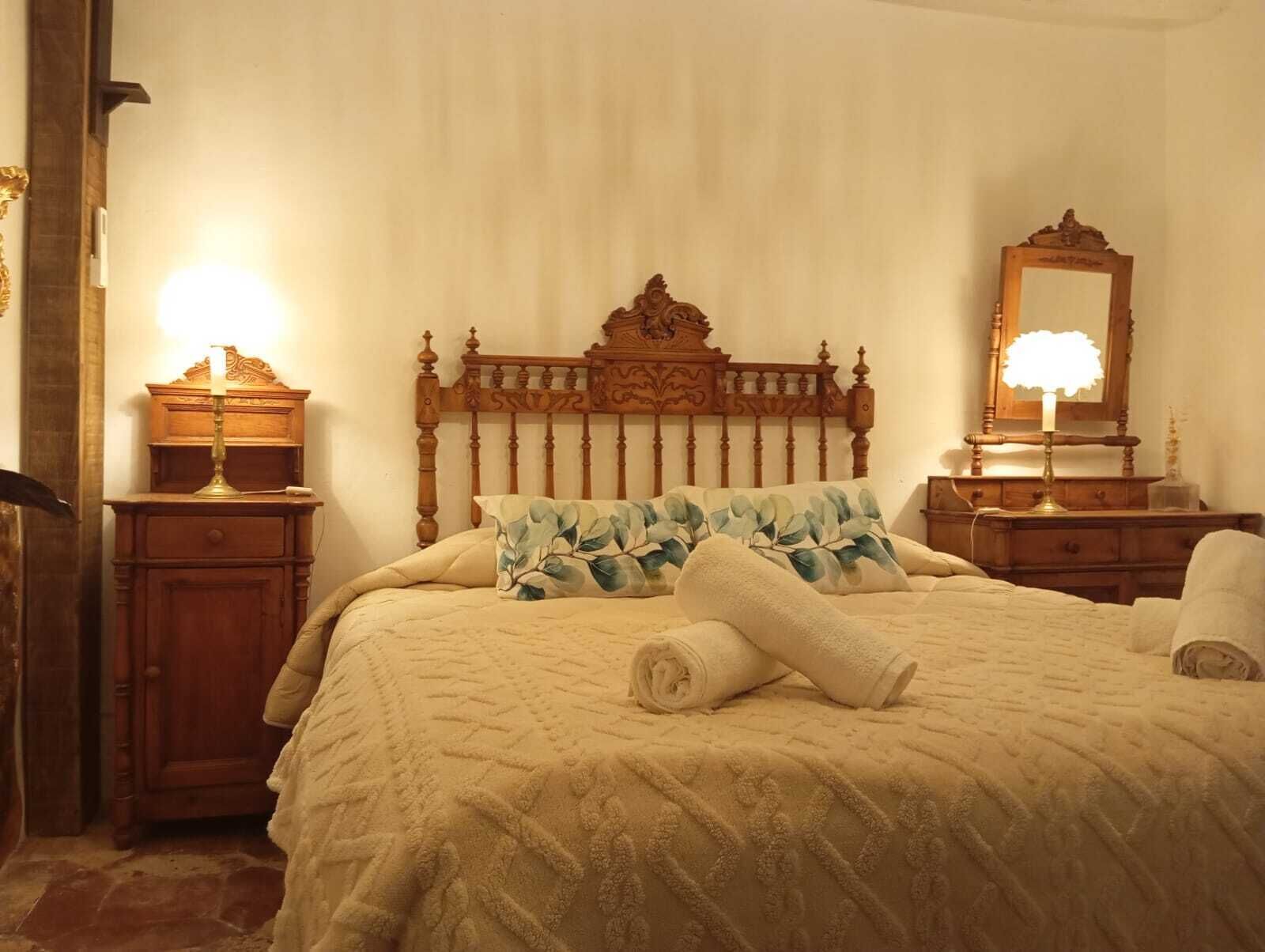 A neatly made bed with a patterned quilt, a wooden headboard, and two bedside lamps.