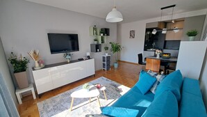 A modern living room with a large TV, a sofa, a coffee table, and a dining area with a kitchen in the background. - Apartment with self- check in, free private parking, WI-FI in brilliant Zagreb (Zagreb)