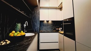 A narrow kitchen with dark countertops, a marble backsplash, and a tiled floor. - Apartment with self- check in, free private parking, WI-FI in brilliant Zagreb (Zagreb)