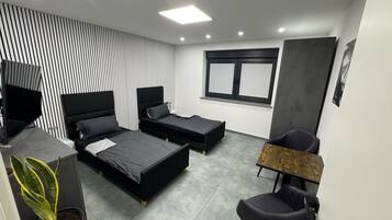 Una camera da letto moderna con due letti, una TV, una scrivania e una sedia.
