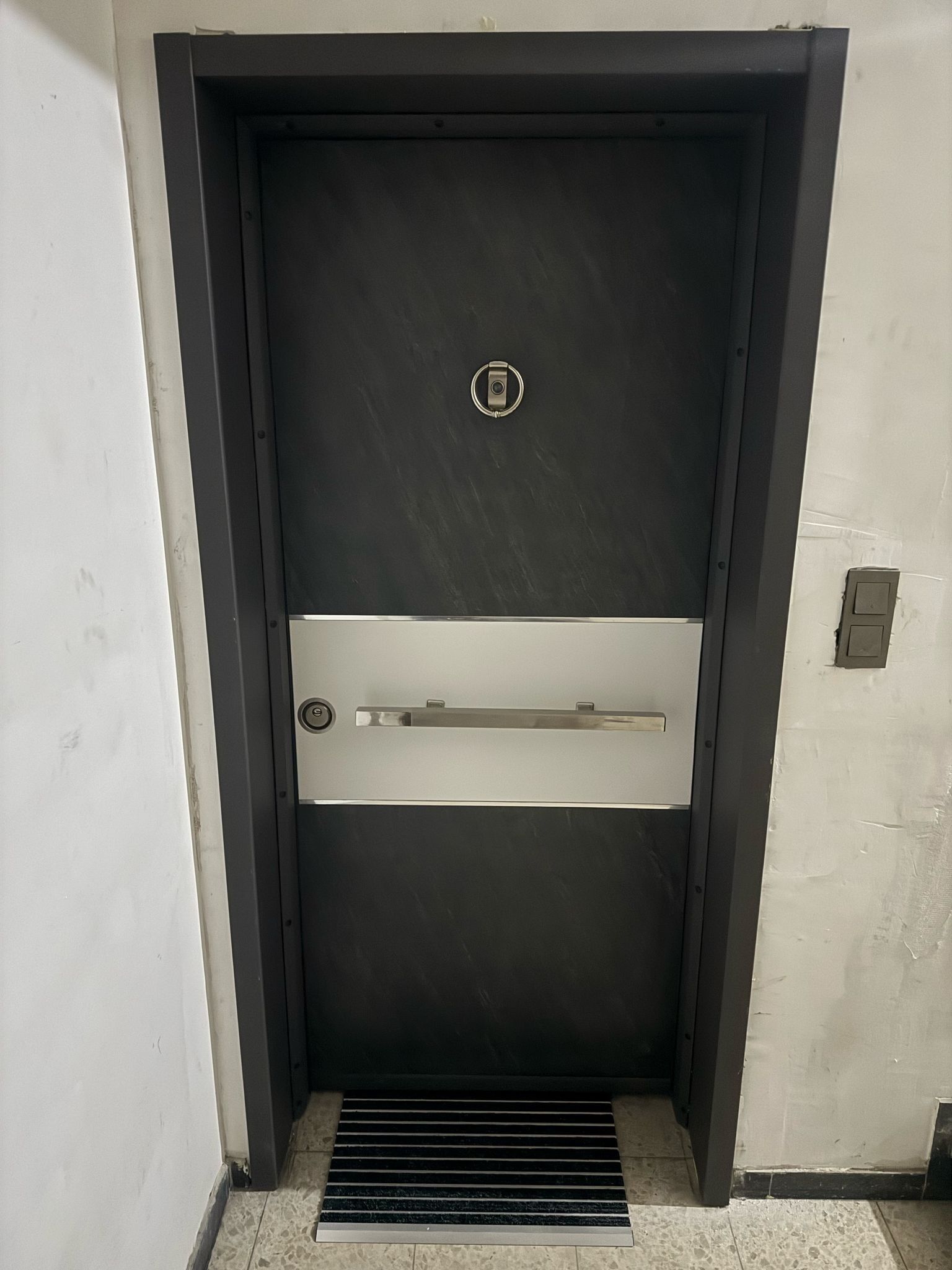 Un ascensor moderno con un pasamanos metálico y un panel de control.