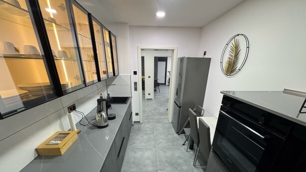 A modern kitchen with a long countertop, a refrigerator, and a dining area with chairs. - Modern Apartments Gelsenkirchen highway A42 and A2 vacation apartment (Gelsenkirchen)