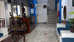 Un soggiorno con pareti blu, una ventola a soffitto, una scala e un estintore.